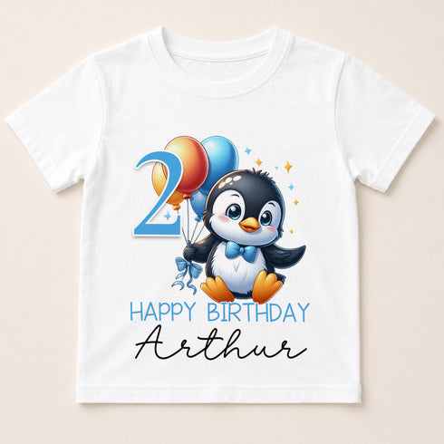 A white t-shirt with a cartoon penguin holding balloons and the number "2" on it, along with the text "Happy Birthday Arthur".