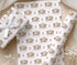 a set of wrapping paper with a repeating pattern of elephants and giraffes, along with the text "Emilly" printed on it. The wrapping paper is displayed on a wooden surface, and there are some white flowers in the background.