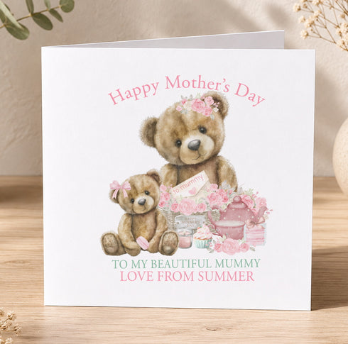 A greeting card with a mother and child teddy bear illustration, along with a floral arrangement and a teapot. The card has a pink and white color scheme and the text "Happy Mother's Day" and "To My Beautiful Mummy Love From Summer" written on it.