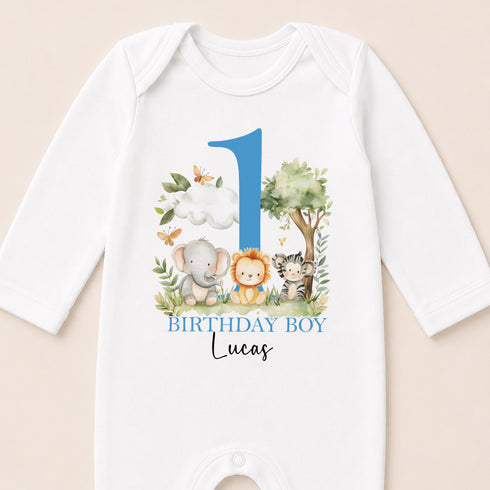 A white onesie with a blue number 1 and illustrations of an elephant, lion, and tiger, along with the text "BIRTHDAY BOY Lucas".