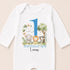 A white onesie with a blue number 1 and illustrations of an elephant, lion, and tiger, along with the text "BIRTHDAY BOY Lucas".