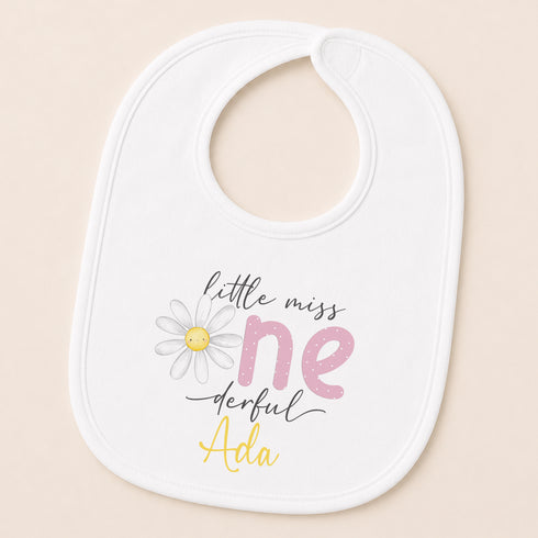 A white baby bib with a printed design and text on it.