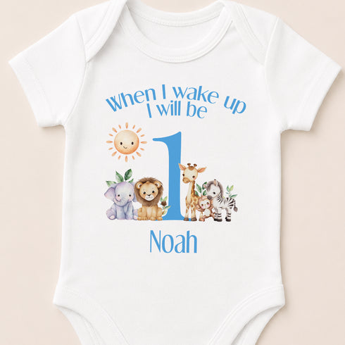 A white baby onesie with a personalized print of a cartoon animal and the text "When I wake up I will be 1 Noah" printed on it.