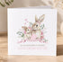 A greeting card featuring a mother rabbit and her baby rabbit, surrounded by pink flowers and greenery, with the text "Happy Mother's Day" and "To my wonderful mummy, love from Lottie" printed on it.