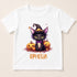 A white t-shirt with a cartoon image of a cat wearing a witch's hat and surrounded by pumpkins, with the name "QPHLIA" written below.