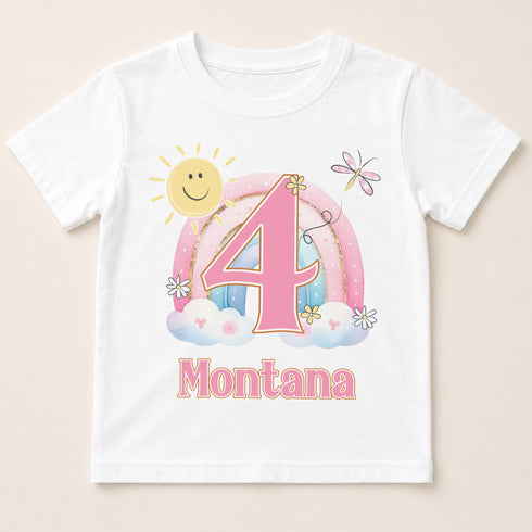 A white t-shirt with a colorful graphic design featuring a sun, clouds, and a rainbow, along with the number 4 and the text "Montana" below it.