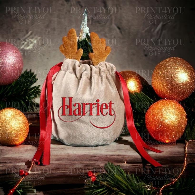 Small velvet drawstring gift bag personalised with a name, printed with a reindeer antler design and finished with a red ribbon