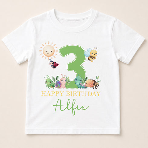 A white t-shirt with a graphic design featuring a large number 3 surrounded by various cartoon insects and animals, along with the text "Happy Birthday Alfie".