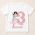 A white t-shirt with a pink illustration of a young girl in a ballerina pose and the number 3, along with the name "Hannah" below the number.