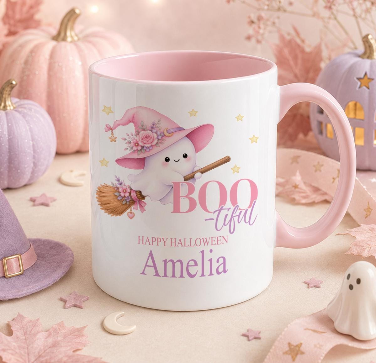 White ceramic mug with pink handle and pink inner, printed with a ghost wearing a floral witch hat and holding a broomstick, Boo-tiful text and the personalised name Amelia.