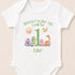 A white baby onesie with a personalized message and illustrations of various animals, including a sun, dragon, and dinosaur.