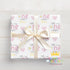 A gift box wrapped in a white ribbon with a pink and yellow floral pattern, featuring the name "Olivia" printed on it.