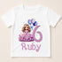 A white t-shirt with a graphic design featuring a princess wearing a purple dress and holding balloons, along with the text "Ruby" below the design.