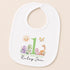 A white baby bib with a printed design featuring a sun, a dragon, and various animals, along with the text "Happy Birthday Riley".