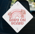 a sign with a pink flower design and the text "BABY ON BOARD" on a white background.