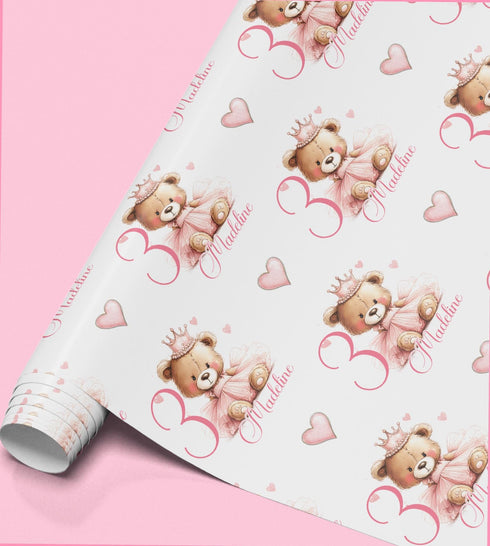 a roll of wrapping paper with a repeating pattern of teddy bears wearing crowns and the text "Madeline" written on them.