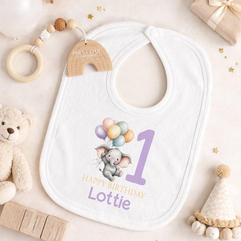 Personalised 1st birthday baby outfit with cute elephant, pastel balloons, purple number 1 and custom name, shown on bib, vest, sleepsuit, t-shirt and white pyjamas.