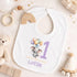 Personalised 1st birthday baby outfit with cute elephant, pastel balloons, purple number 1 and custom name, shown on bib, vest, sleepsuit, t-shirt and white pyjamas.