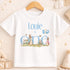 A white t-shirt with a personalized text and illustrations, including a rabbit and balloons, is displayed on a wooden hanger.