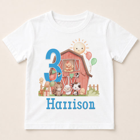 A white t-shirt with a colorful illustration of a barn, farm animals, and a number 3.