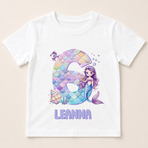 A white t-shirt with a design featuring a mermaid character and the number 6.