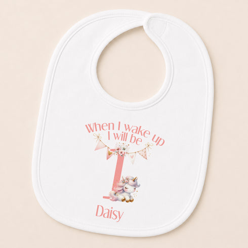 A white baby bib with a personalized design featuring a unicorn and the text "When I wake up I will be Daisy".