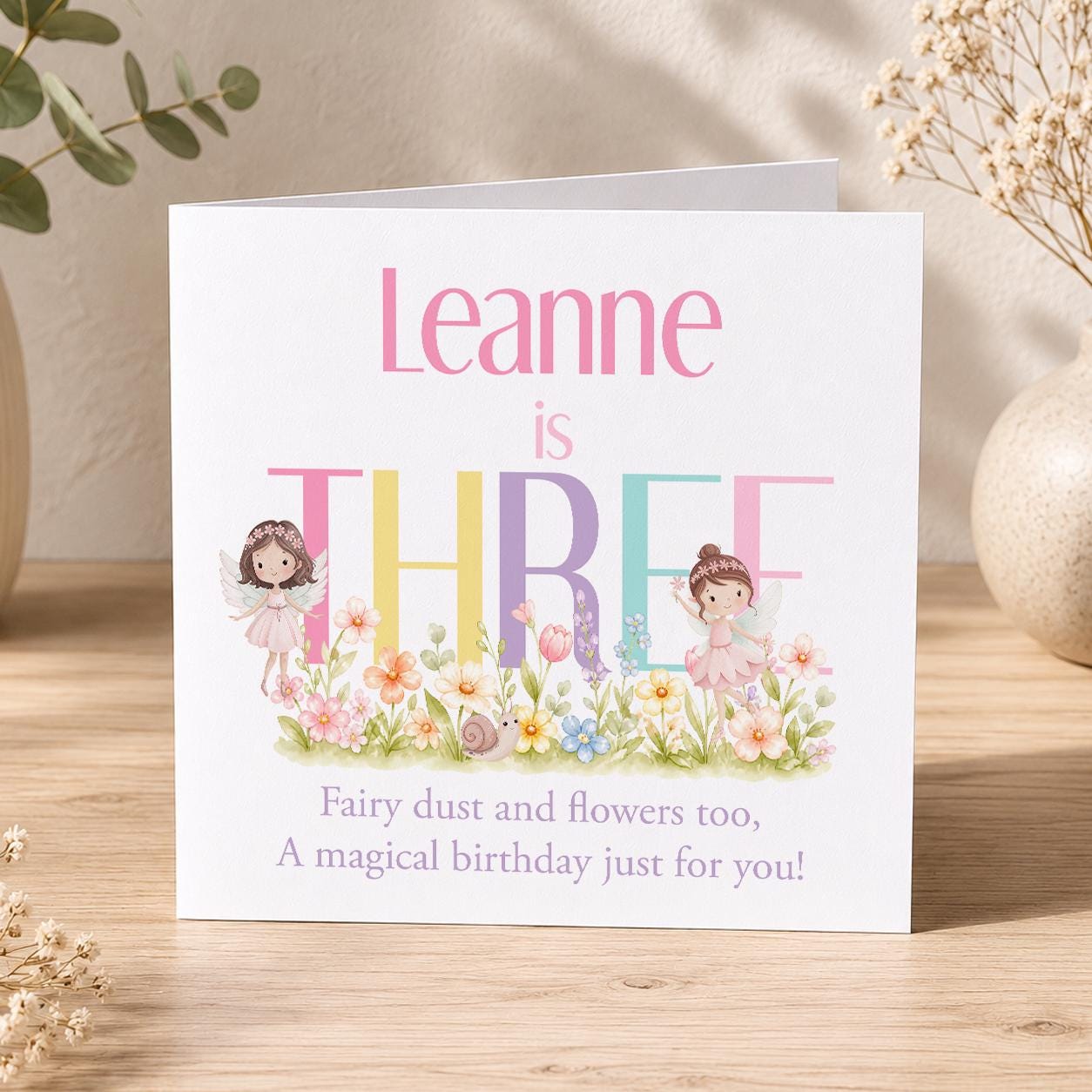 Square personalised fairy birthday card featuring a pastel floral fairy design with rainbow-coloured birthday lettering.