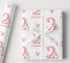 a gift wrapped in pink and white paper with a white ribbon.