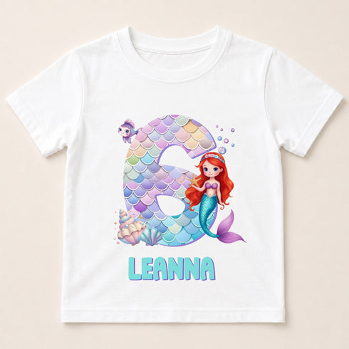 A white t-shirt with a design featuring a mermaid character and the number 6.
