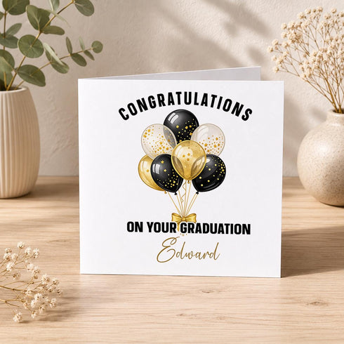 Personalised graduation card with black, gold and clear confetti balloons, congratulations wording and a custom name on a square greeting card.