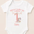 A white onesie with a pink unicorn and the text "When I wake up I will be up" printed on it.