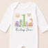 A white onesie with a personalized birthday message and cartoon animal illustrations.