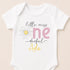 A white baby onesie with a flower design and text printed on it.