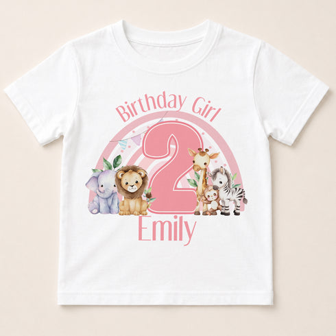 A white t-shirt with a pink graphic design featuring a large number "2" surrounded by various animals, including a lion, giraffe, zebra, and elephant. The text "Birthday Girl Emily" is written above the graphic.