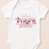 A white baby onesie with the text "Indie's FIRST RODEO" printed on it.