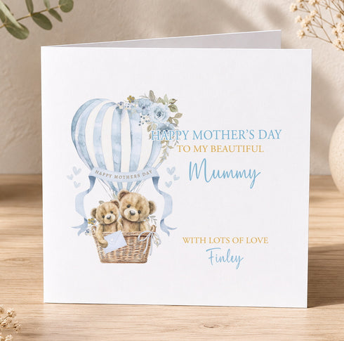 A greeting card with a mother and baby teddy bear illustration, along with a hot air balloon and floral design. The card has a message that reads "Happy Mother's Day to my beautiful Mummy with lots of love Finley".
