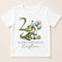 A white t-shirt with a cartoon image of a green alligator wearing a party hat and holding balloons, along with the text "Happy Birthday Layton" printed on it.
