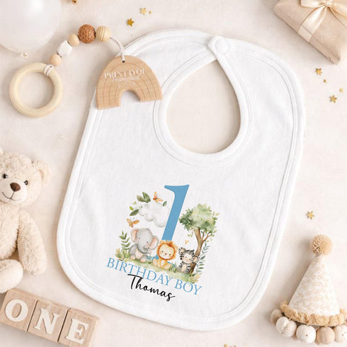 Personalised 1st birthday boy outfit with blue number 1, safari animals, elephant, lion, zebra, tree and custom name, shown on bib, vest, sleepsuit, t-shirt and white pyjamas.