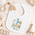 Personalised 1st birthday boy outfit with blue number 1, safari animals, elephant, lion, zebra, tree and custom name, shown on bib, vest, sleepsuit, t-shirt and white pyjamas.