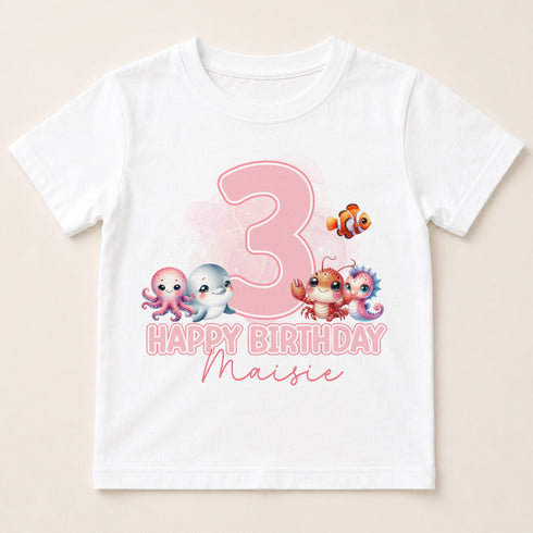 A white t-shirt with a pink number 3 and a happy birthday message, along with illustrations of three cute cartoon animals.
