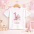Personalised 1st birthday girl outfit with pink number 1, cute cupcake design, happy birthday text and custom name, shown on sleepsuit, t-shirt, vest, pyjamas and bib.