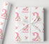 a gift wrapped in pink and white paper with a white ribbon.