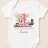 A white baby onesie with a pink and green animal print and the text "BIRTHDAY GIRL Eva" printed on it.