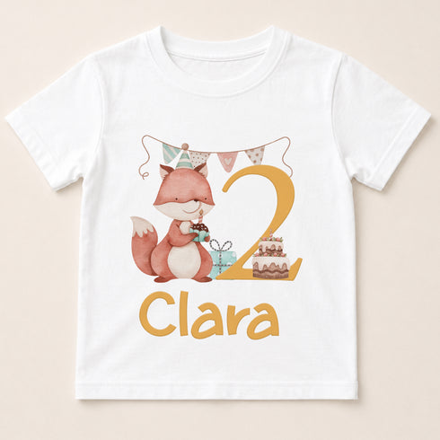 A white t-shirt with a cartoon fox and a birthday cake, along with the name "Clara" printed on it.
