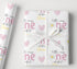 a gift wrapped in a white paper with a pink and yellow floral pattern, and a white ribbon tied around it.