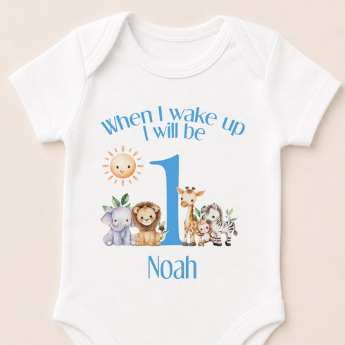 A white baby onesie with a printed design of various animals, including a lion, giraffe, elephant, and zebra, along with the text "When I wake up I will be Noah".