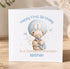 A white greeting card with a teddy bear and a balloon, celebrating a first birthday.