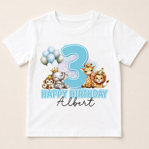 A white t-shirt with a birthday theme featuring a large number 3, surrounded by cartoon animal characters such as a giraffe, lion, and monkey.