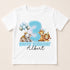 A white t-shirt with a birthday theme featuring a large number 3, surrounded by cartoon animal characters such as a giraffe, lion, and monkey.
