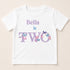 A white t-shirt with the text "Bella is two" printed on it, along with a design of butterflies.